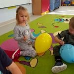 Dzieci podczas zabawy na kolorowym dywanie podczas zajęć w przedszkolu z balonikami