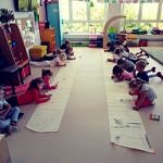 dzieci rysują na podłodze na długich rolkach papieru