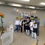 Dzieci w strojach galowych i czapkach stoją w rzędzie; u góry napis ślubowanie