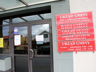 Drzwi do Urzędu Gminy w Woli Krzysztoporskiej, obok czerwone tablice informacyjne