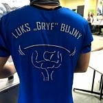 Plecy zawodnika w niebieskiej koszulce, a na niej napis LUKS Gryf Bujny