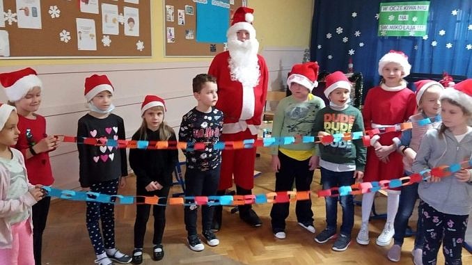 Grupa dzieci z Mikołajem - trzymają kolorowy łańcuch z papieru
