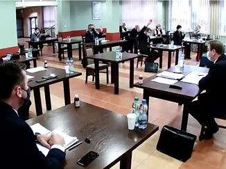 Sesja Rady Gminy Wola Krzysztoporska. Radni i władze gminy siedzą przy oddzielnych stolikach w maseczkach