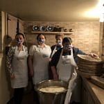 Cztery kobiety w fartuchach i maseczkach przy misie z ciastem chlebowym