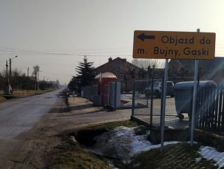 Droga i żółty znak objazdu z napisem: objazd m. Bujny, Gąski