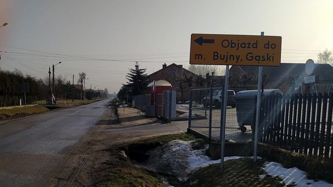 Droga i żółty znak objazdu z napisem: objazd m. Bujny, Gąski