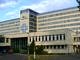 Front szpitala im. Kpernika w Łodzi; szary, duży budynek; nad wejściem logo w postaci niebieskiego podwójnego krzyża