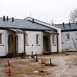 Budynki komunalne w budowie - białe budynki pokryte dachem; ganek podparty drewnianymi belkami
