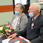 starsi ludzie - para małżeńska - odbierają od przedstawicieli gminy madal za długoletnie pożycie małżeńskie; ootrzymują też kwiaty i prezent od przedstawicieli gminy