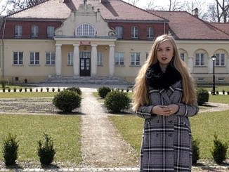 Młoda kobieta stoi na tle dworku - Szkoły Podstawowej w Parzniewicach