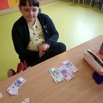 Dziecko nad stołem z banknotami i wyciętymi z papieru monetami