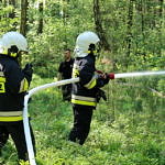 Strażacy podają wodę na teren pożaru