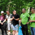 Grupa ludzi (część w zielonych koszulkach Leszy) przygotowuje się do wyjścia w teren