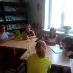 Dzieci w bibliotece czytaja książki przy stole