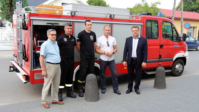 Nowy samochód strażacki a przed nim predstawiciele strażaków i wót gminy