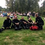Uczestnicy odpoczywają na łące pod pomnikiem na Górach Borowskich - na pierwszym planie pięcioro strażaków