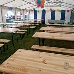 Drewniane stoły i ławki pod białym namiotem