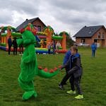 Kolorowe dmuchańce i żywa maskotka - zielony smok - podczas zabawy z dziećmi