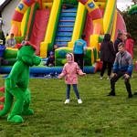 Kolorowe dmuchańce i żywa maskotka - zielony smok - podczas zabawy z dziećmi