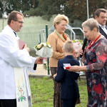Dzieci wręczają kwiaty księdzu, wójtowi i przewodniczącej RG