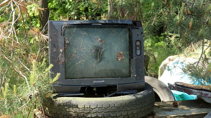 stary telewizor ustawiony na oponach na tle lasu