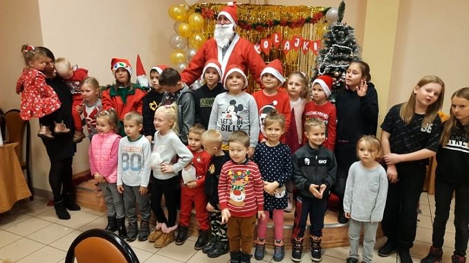 Dzieci w mikołajkowych czapkach i czerwonych strojach z Mikołajem