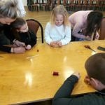 Dzieci przy stołach robią biżuterię z różnych materiałów