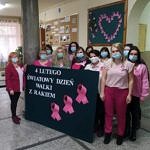Grupa kobiet w maskach i różowych bluzkach z wielkim plakatem