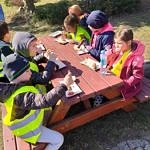 Dzieci przy stole piknikowym jedzą kiełbaski