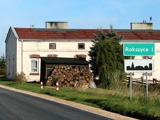 Budynek komunalny w Rokszycach - pred nim składzik na drewno iznak drogowy Rokszyce I