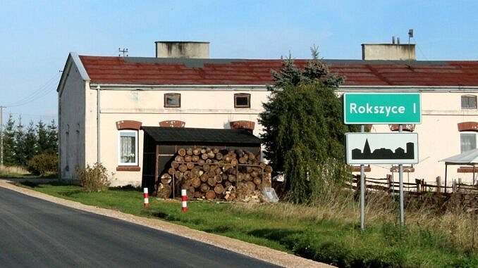 Budynek komunalny w Rokszycach - pred nim składzik na drewno iznak drogowy Rokszyce I