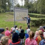 Mężcztzna przy tablicy na Górach Borowskich pokazuje coś przedszkolakom