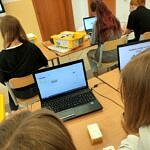 Uczniowie przy komputerach i pomocach dydaktycznych