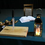 stół deska nóż świece lampion i książka