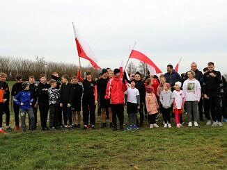 Zawodnicy na starcie biegu OPEN z flagami biało-czerwonymi