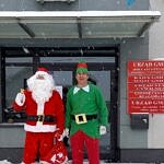 Mikołaj z brodą i Elf w zielonym stroju przed budynkiem UG