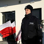 policjant przed posterunkiem przy flagach