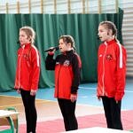 3 dziewczynki w czerwonych bluzach strazackich śpiewają piosenkę