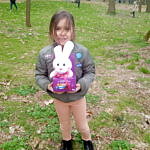 Dzieci podczas poszukiwania jajeczek i słodyczy w parku - dziewczynka z zajaczkiem