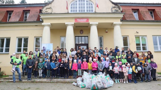 Zdjęcie grupowe dzieci i opiekunów przzed szkołą w Parzniewicach; obok worki ze śmieciami