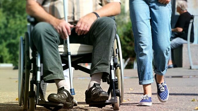 Nogi niepełnosprawnego na wózku i osoby idącej obok