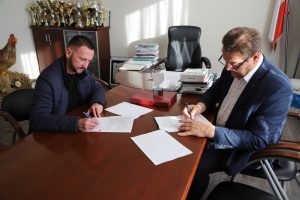 Ksiądz proboszcz Artur Trznadel i wójt gminy Wola Krzysztoporska Roman Drozdek podpisują umowę na przekazanie dotacji Parafii Gomulin